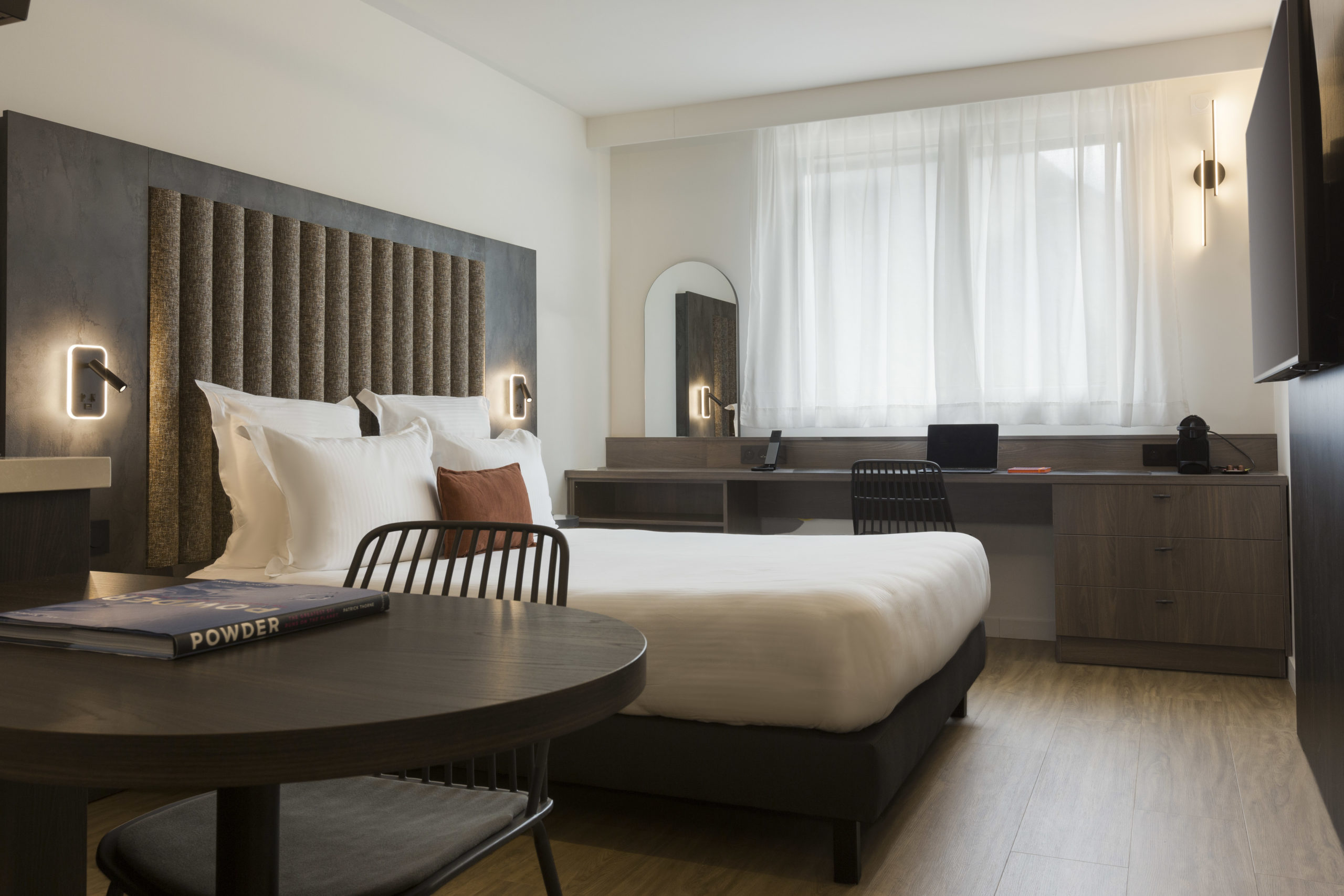 Studio confort lit double avec lit, bureau, télévision et grande fenêtre au Nehô Suites Saint-Jean-de-Maurienne.