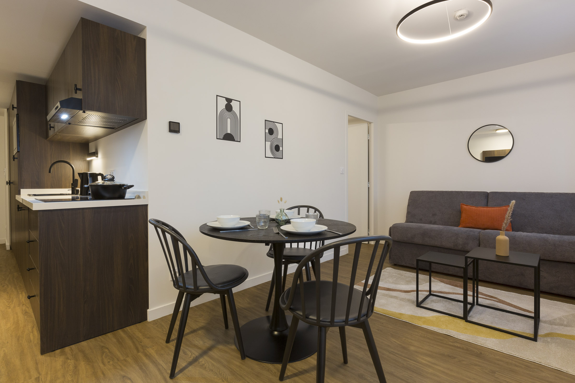 Séjour 2 pièces avec cuisine équipée, table, chaises et canapé au Nehô Suites Saint-Jean-de-Maurienne.