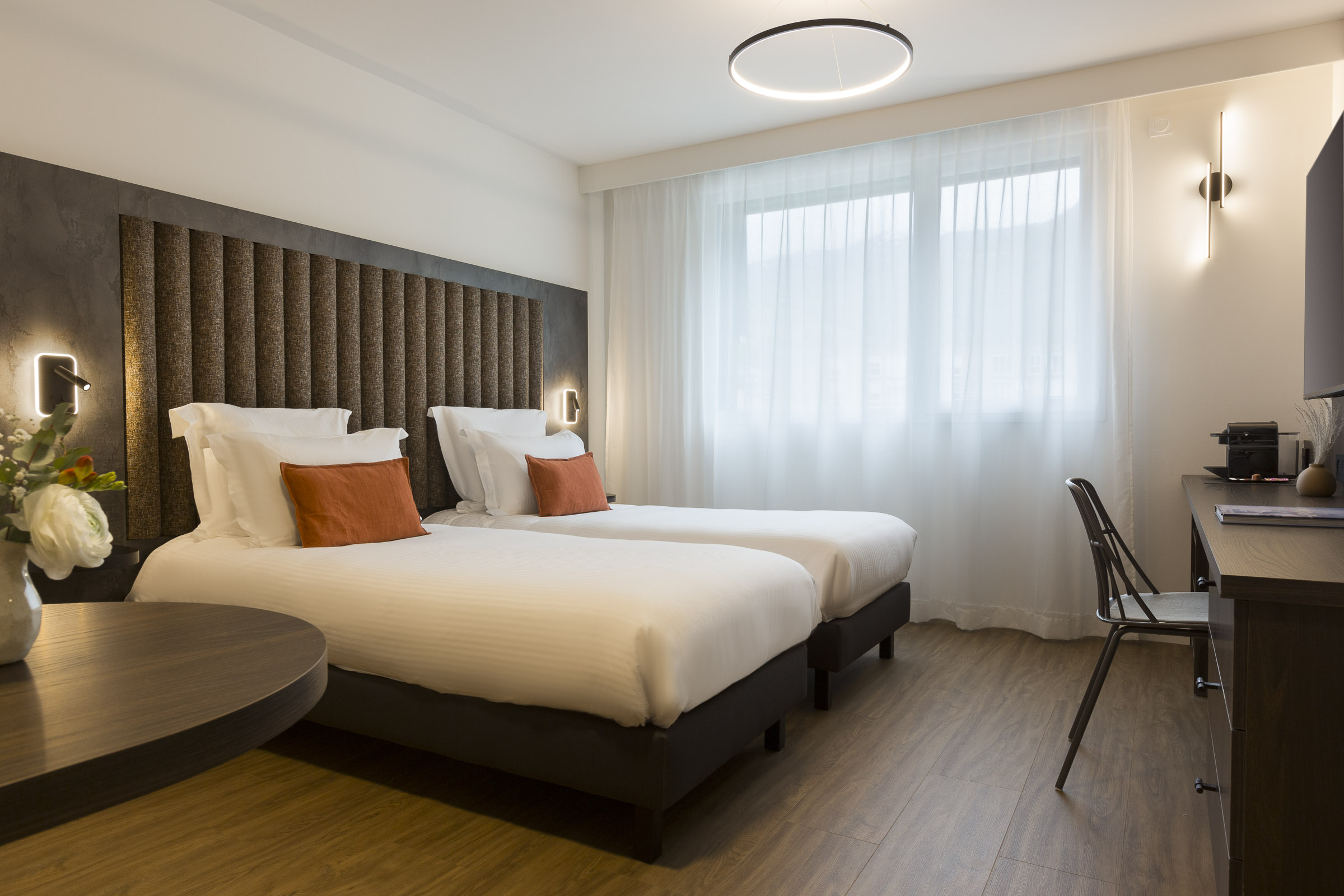 Chambre twin studio supérieur avec deux lits séparés, bureau et fenêtre au Nehô Suites Saint-Jean-de-Maurienne.